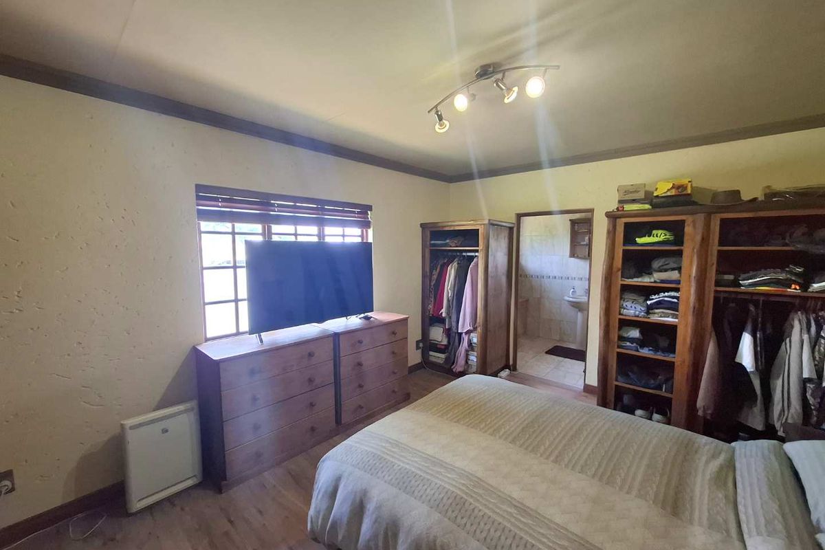 A bedroom featuring wooden flooring, a multi-directional ceiling light fixture, and an en-suite bathroom entrance.
