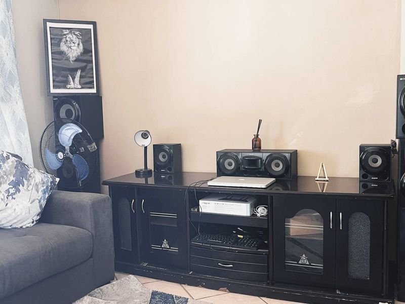 A living room area featuring neutral wall paint and tiled flooring, currently set up as a media space.