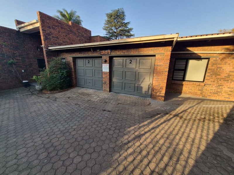 Front exterior view of a cluster property featuring a double garage with sectional doors and a paved driveway.