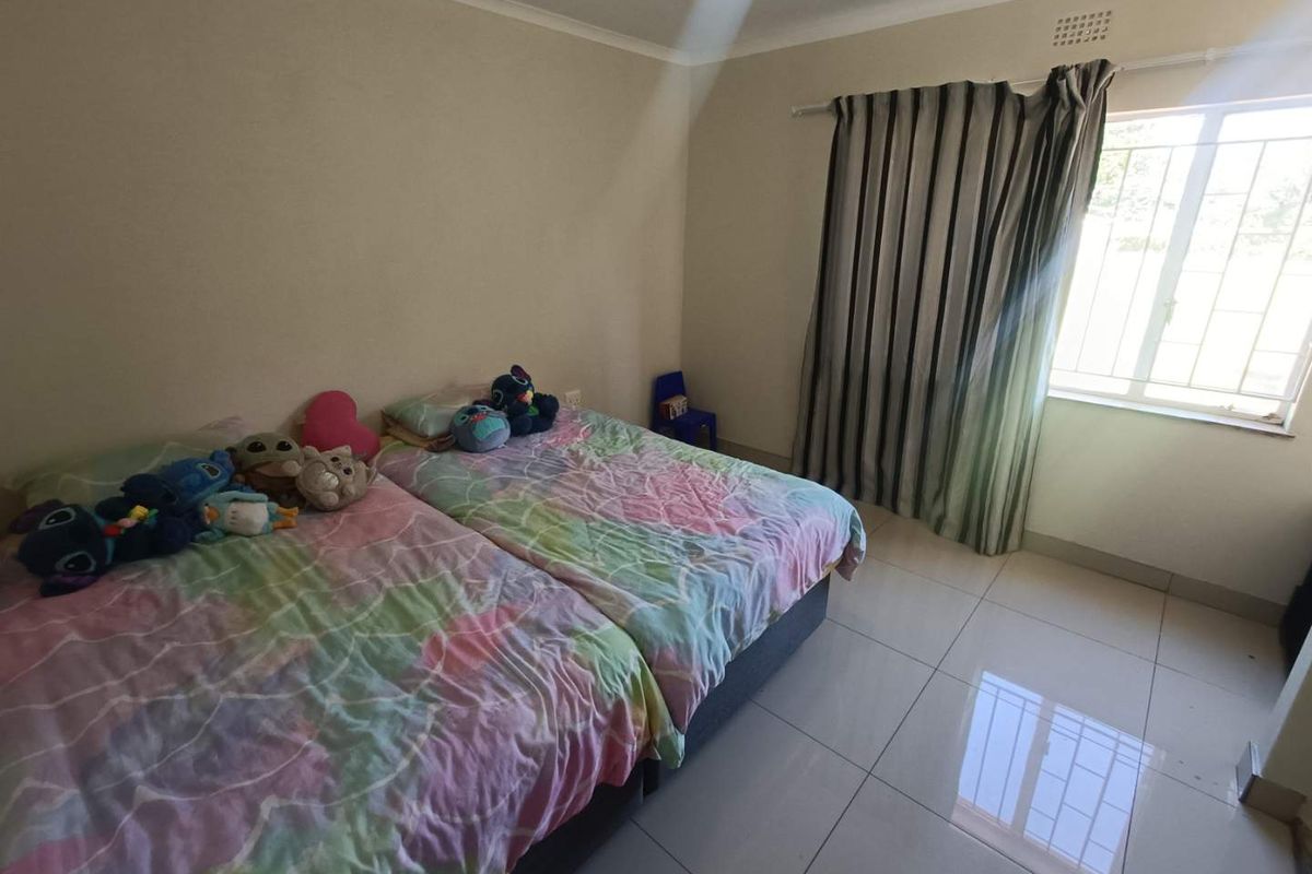A bedroom featuring tiled flooring, a window with security bars, and a ceiling vent.