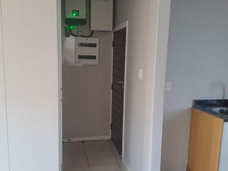 A dedicated utility space featuring a wall-mounted inverter and battery backup system, providing essential power infrastructure for the apartment.