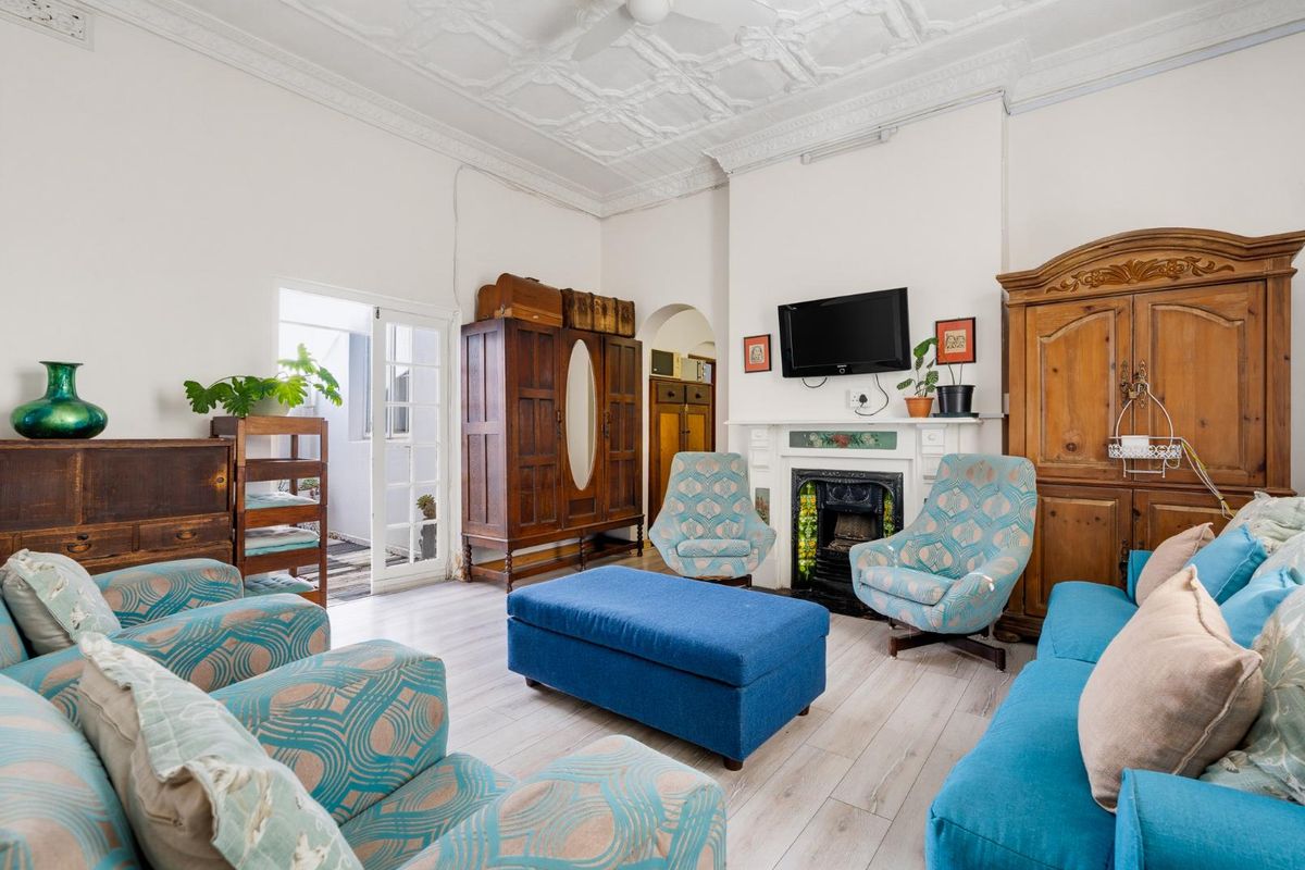 Spacious living room featuring an ornate plaster ceiling, a classic fireplace with mantelpiece, and direct access to an outdoor area through french doors.