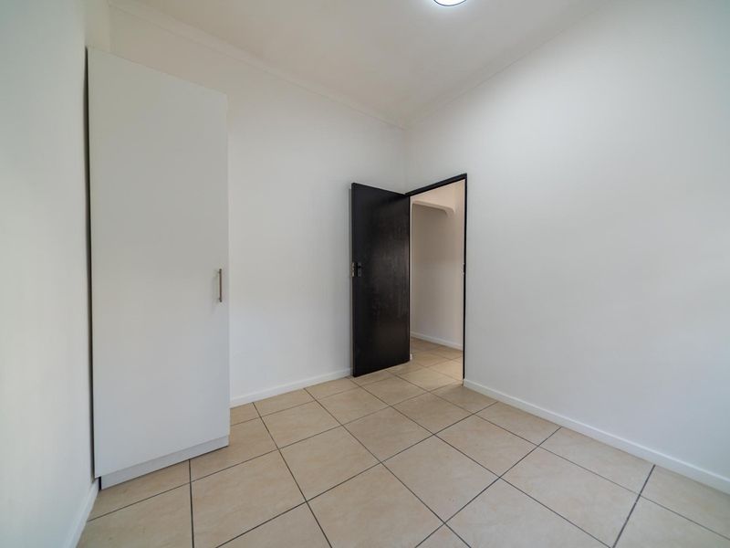 A clean, empty bedroom featuring neutral tiled flooring and a built-in wardrobe, offering a blank canvas for personalization.