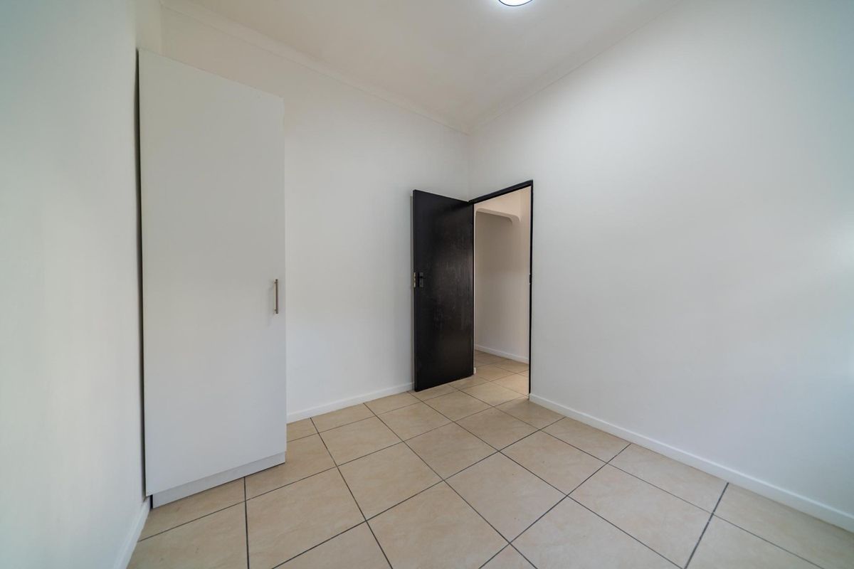 A clean, empty bedroom featuring neutral tiled flooring and a built-in wardrobe, offering a blank canvas for personalization.