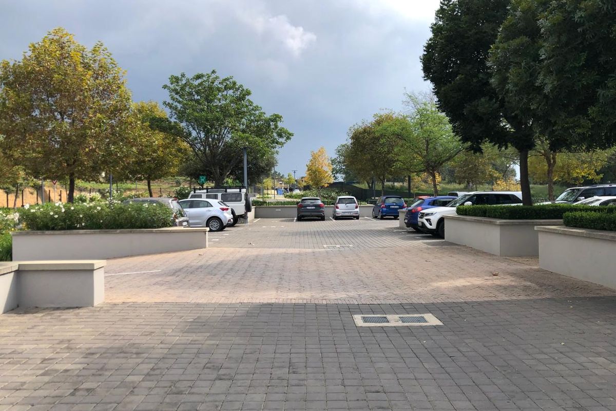 A well-maintained paved parking area featuring structured retaining walls and established landscaping, providing convenient access to the office premises.