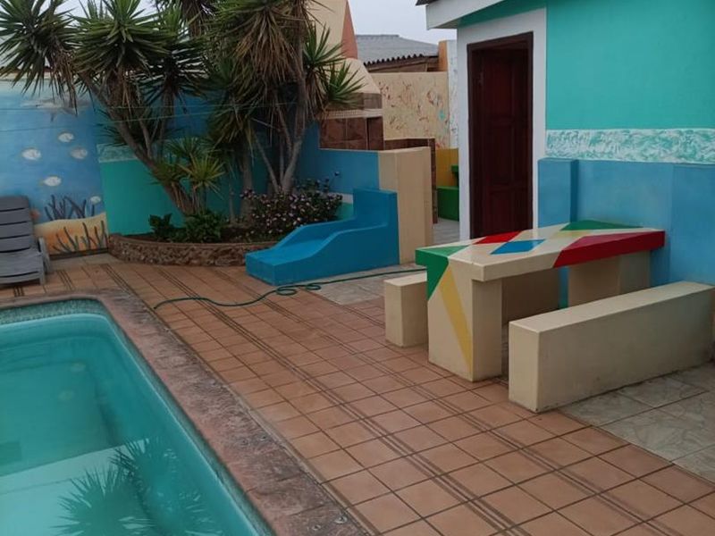Outdoor pool area featuring a tiled deck, built-in concrete seating, and a raised garden bed, providing a functional space for guest relaxation.