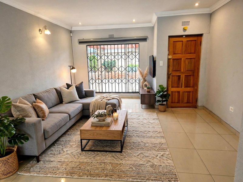 A well-maintained living room featuring tiled flooring, recessed lighting, and a secure entrance with a solid timber door.