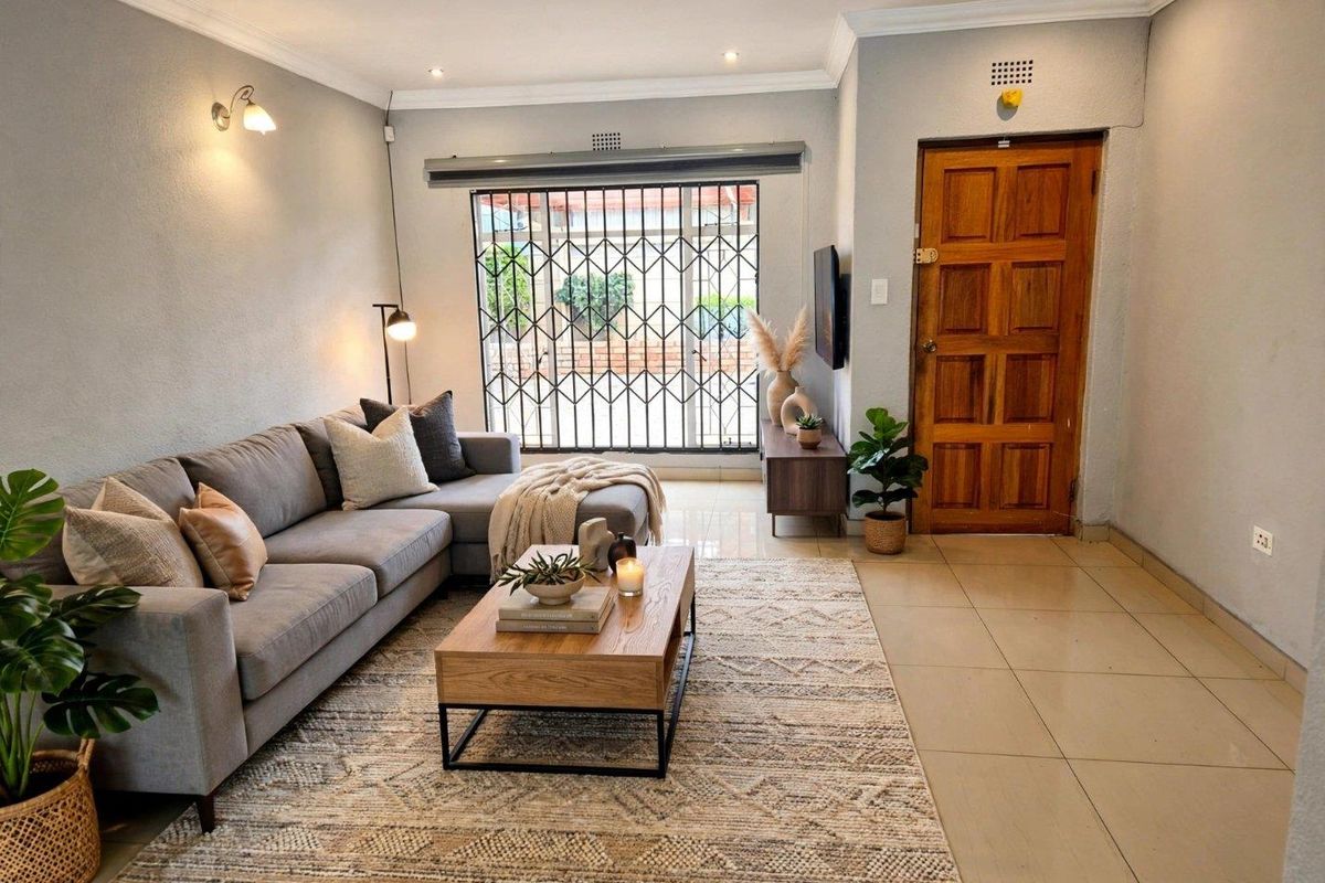 A well-maintained living room featuring tiled flooring, recessed lighting, and a secure entrance with a solid timber door.