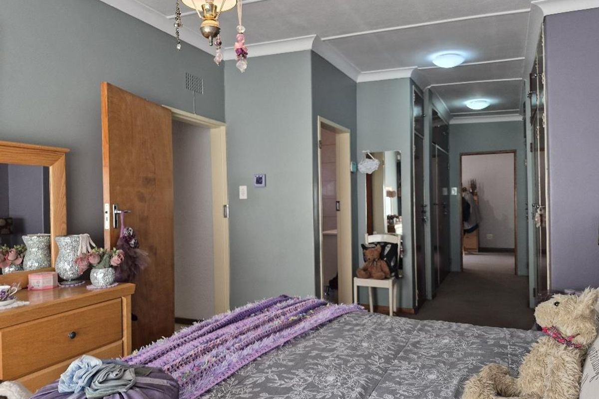 A bedroom featuring built-in cupboards, cove cornicing, and neutral wall finishes, providing a functional layout with direct access to an adjoining space.