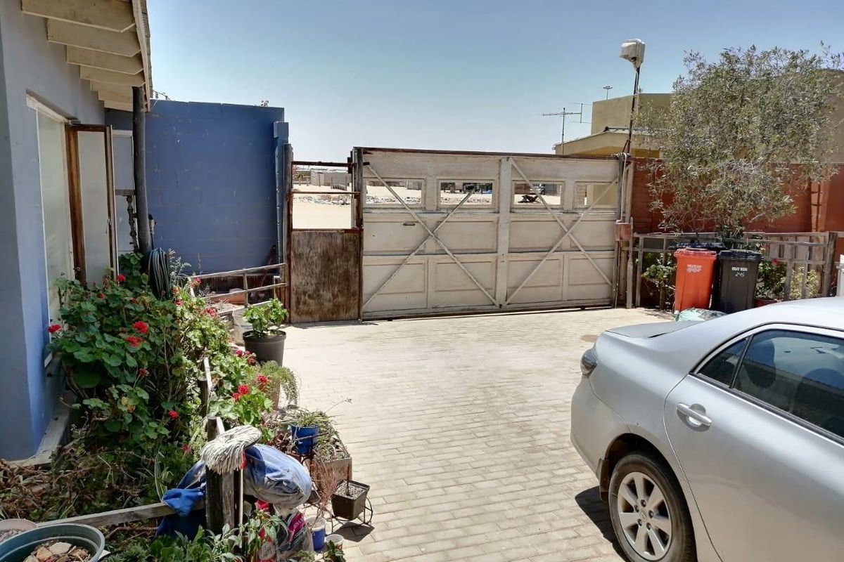 Exterior view of a paved driveway area featuring a large, weathered gate and direct access to the property's side elevation.