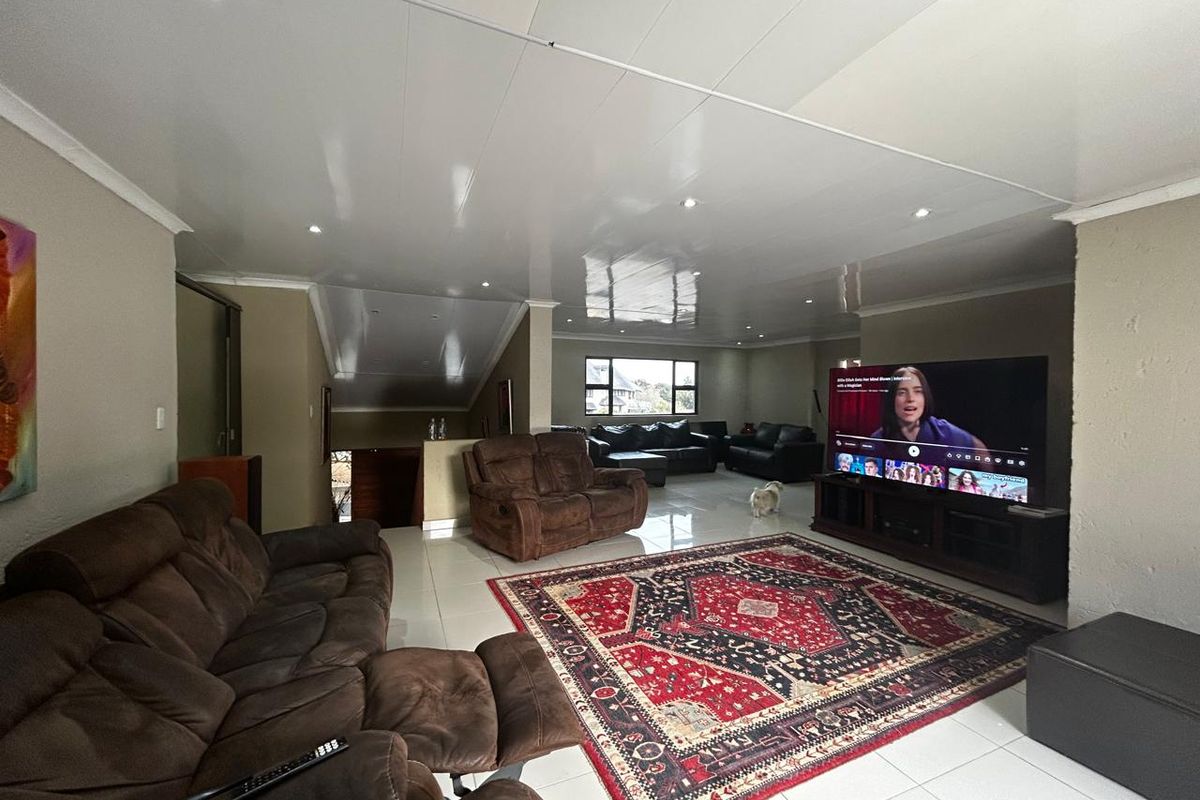 Spacious living room featuring high-gloss ceiling panels, recessed downlighting, and polished floor tiles, providing a bright and open area for relaxation.