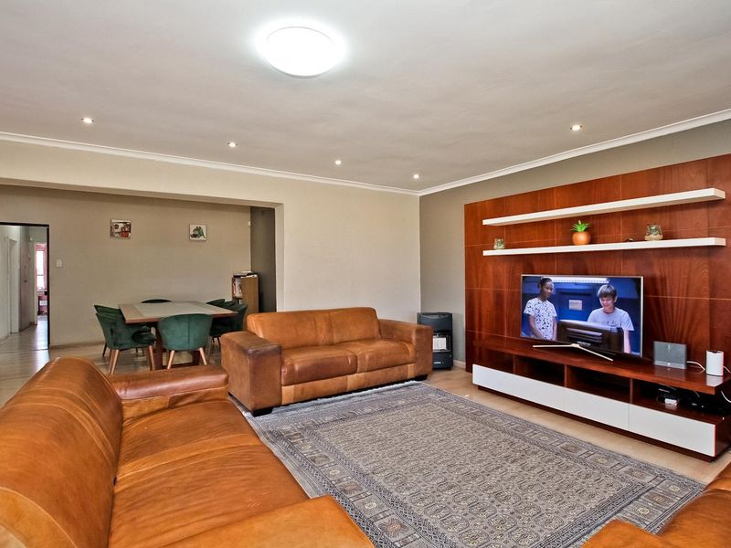 Spacious open-plan living and dining area featuring a custom built-in media wall, recessed lighting, and durable laminate flooring.