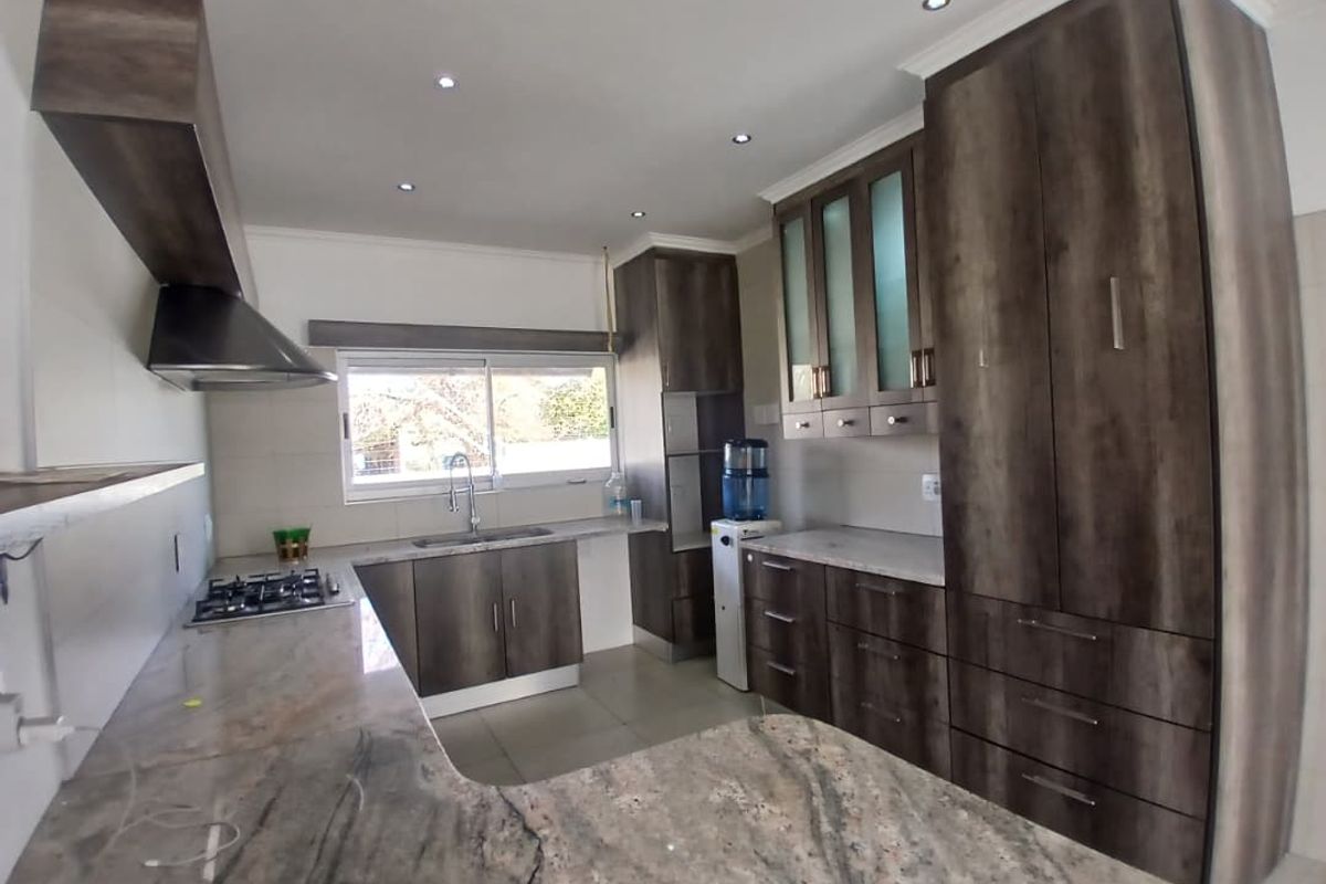 Modern kitchen featuring dark wood cabinetry, granite countertops, a gas hob, and a stainless steel extractor fan with recessed lighting.