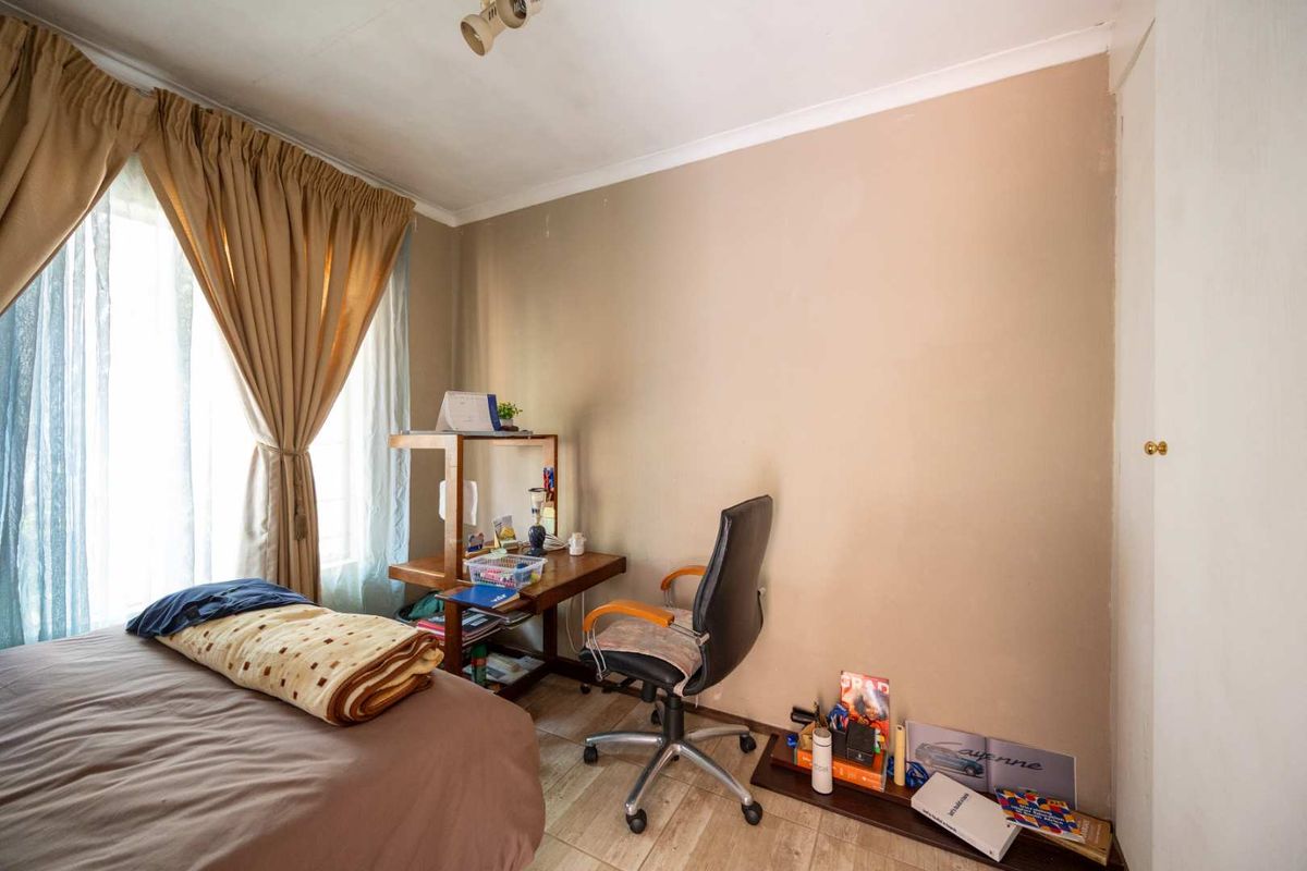 A functional bedroom featuring tiled flooring, a built-in cupboard, and natural light from the window.