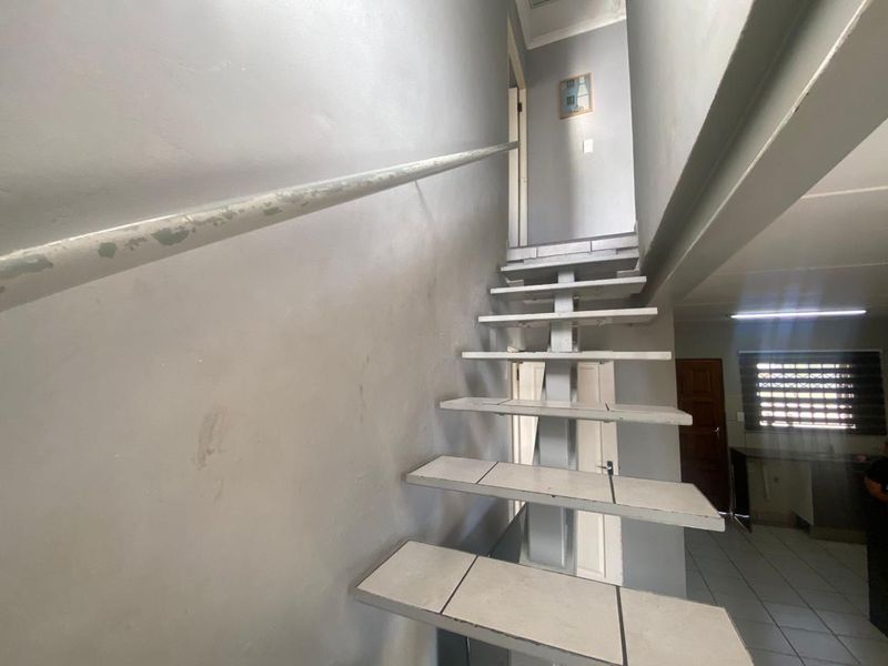 A staircase featuring tiled treads and a metal handrail, leading to an upper level within the home.