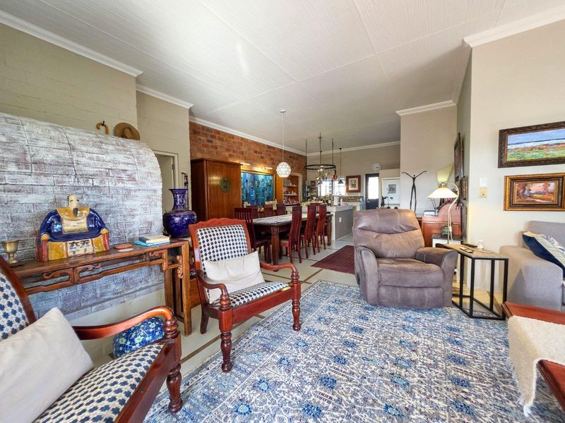 Spacious open-plan living and dining area featuring an exposed brick wall, a unique brick fireplace, and a functional kitchen island.