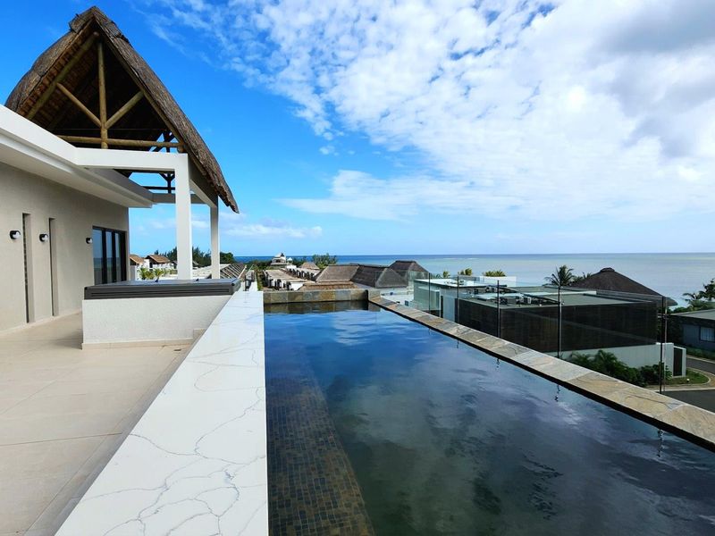 A luxurious penthouse terrace featuring an infinity pool with panoramic ocean views, complemented by a covered patio area and modern architectural finishes.