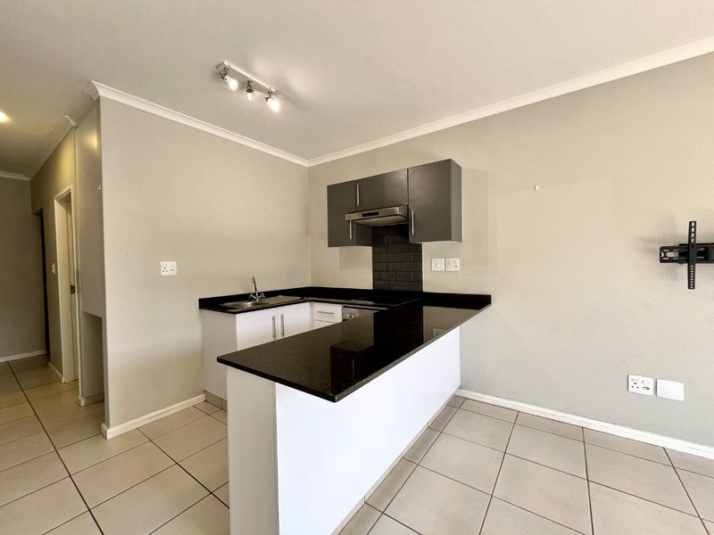 A clean, modern kitchen featuring dark cabinetry, granite countertops, a subway tile backsplash, and tiled flooring in an open-plan layout.