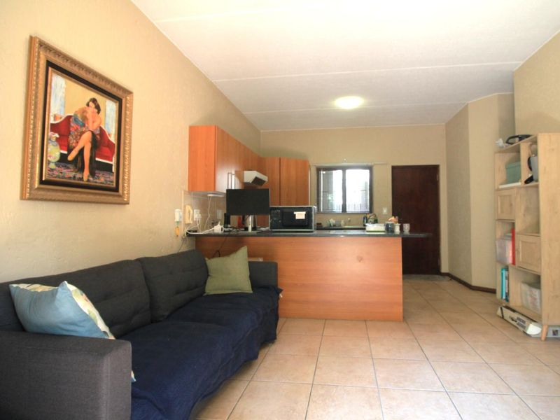 Open-plan living area featuring tiled flooring and a functional kitchen with built-in cabinetry and a breakfast counter.