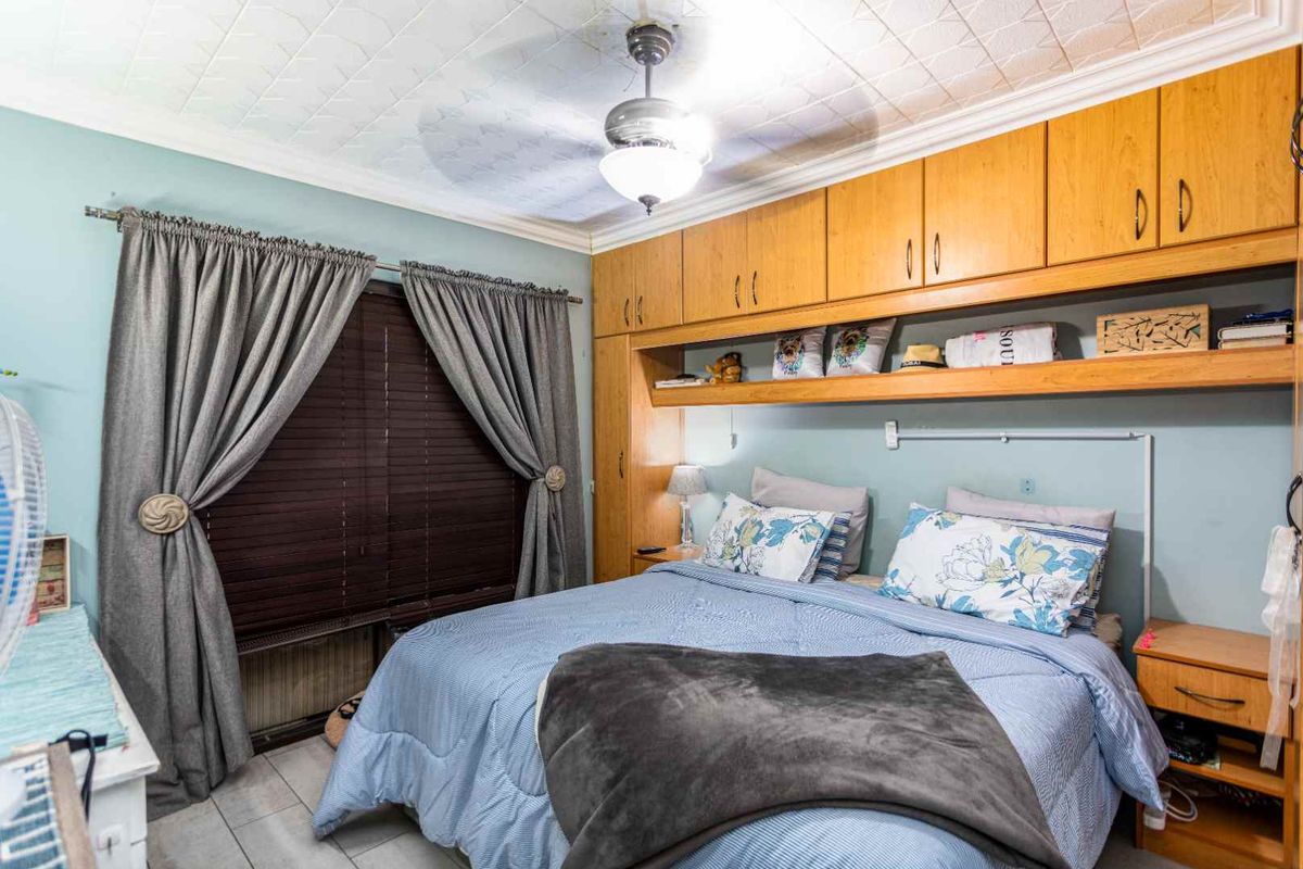 A bedroom featuring built-in wooden cabinetry and overhead storage, a ceiling fan, and tiled flooring.