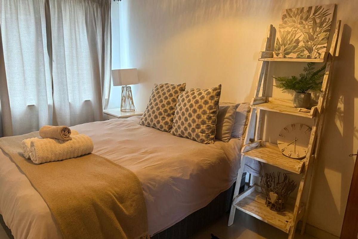 A cozy bedroom featuring neutral wall finishes, tiled flooring, and a window with curtain tracks.