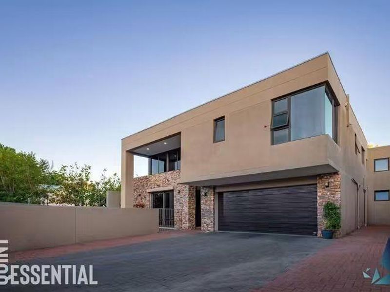 Modern double-story residence featuring stone cladding, a spacious paved driveway, and an integrated double garage.
