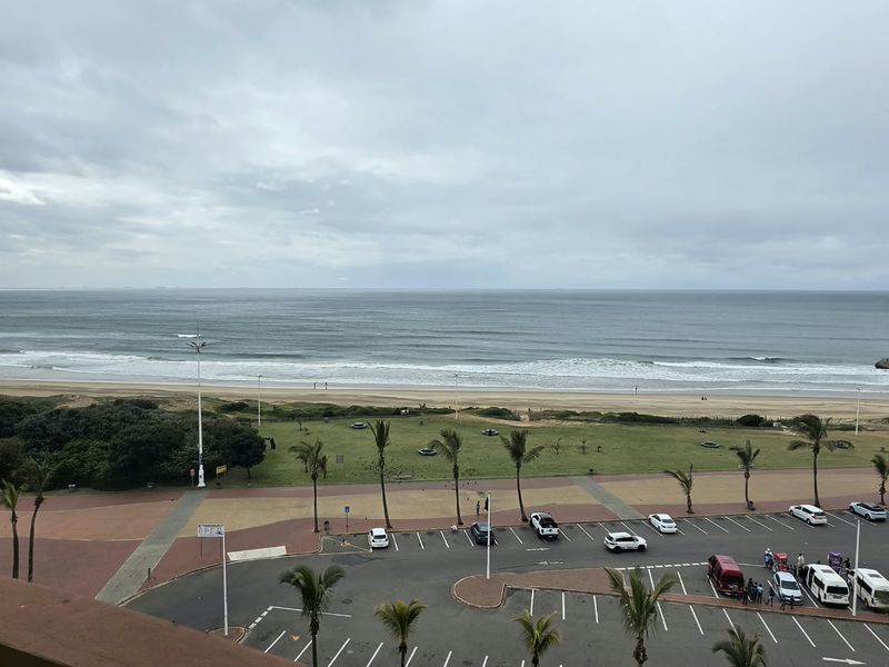 Elevated panoramic view overlooking the beach, promenade, and parking area, showcasing the coastal location and proximity to the ocean.