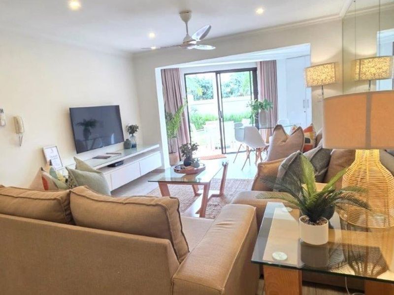 A bright and inviting living room featuring recessed lighting, a ceiling fan, and a large sliding glass door leading to an outdoor patio area.