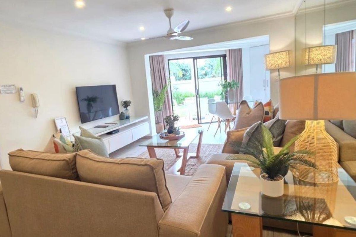 A bright and inviting living room featuring recessed lighting, a ceiling fan, and a large sliding glass door leading to an outdoor patio area.