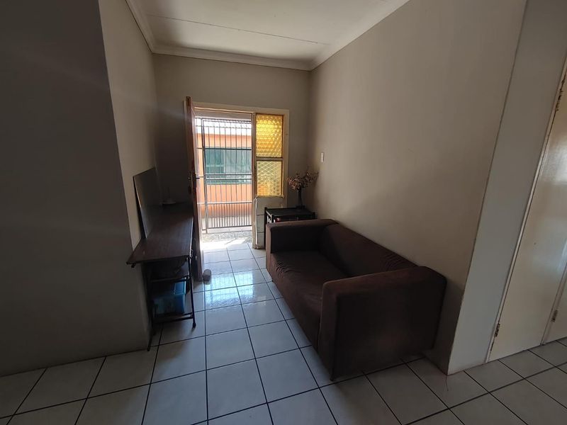 A living area featuring tiled flooring, cornicing, and direct access to an exterior space through a security gate.