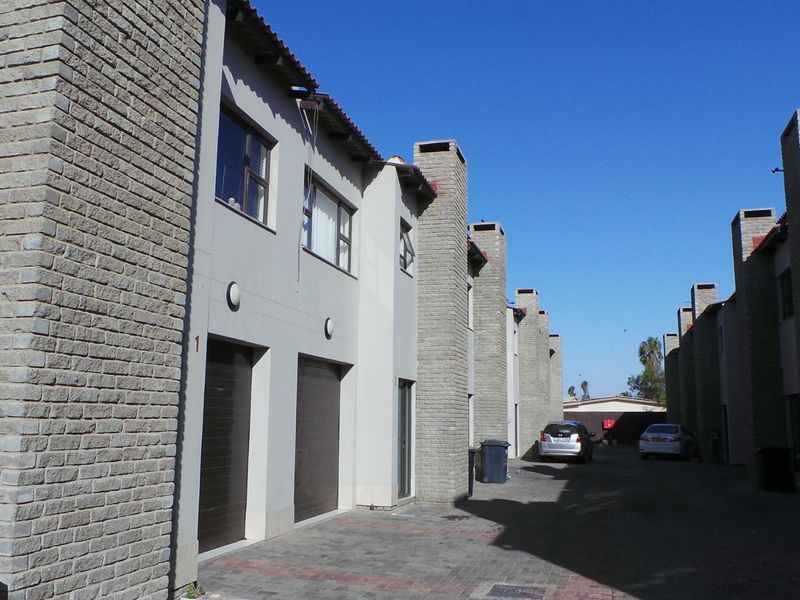 Exterior view of a townhouse complex featuring brick facades, paved driveway access, and integrated garage doors.