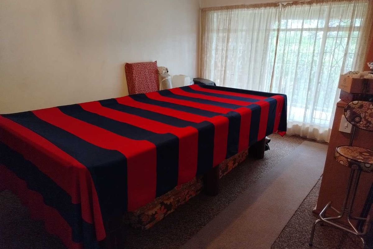 A living area featuring carpet flooring and a large window with curtains, offering potential for versatile use as a lounge or entertainment space.