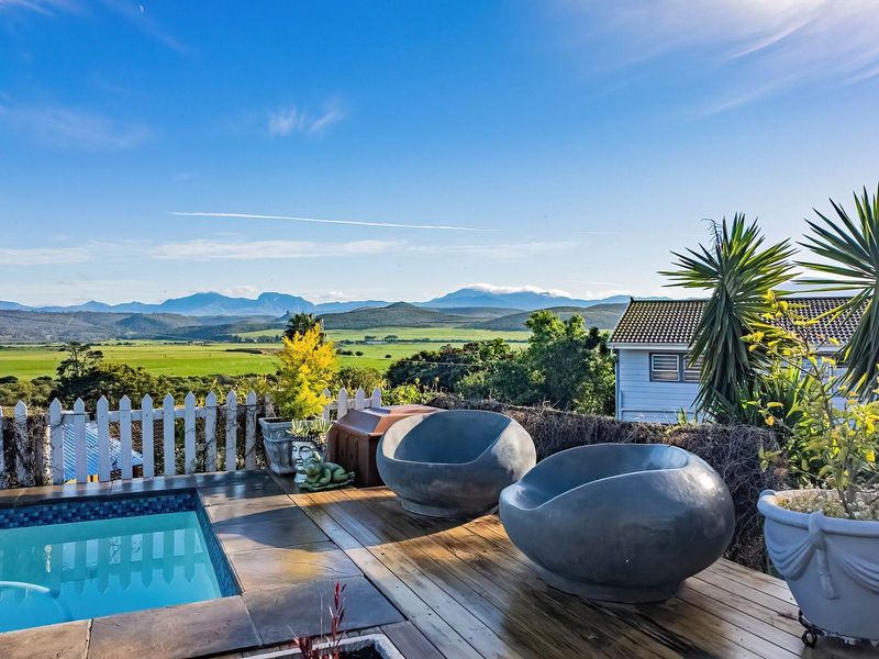 Outdoor pool area featuring wooden decking, a tiled pool surround, and a picket fence with expansive mountain and landscape views.