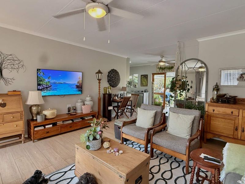 Spacious open-plan living area featuring tiled flooring, ceiling fans, and direct access to an outdoor patio through sliding glass doors.