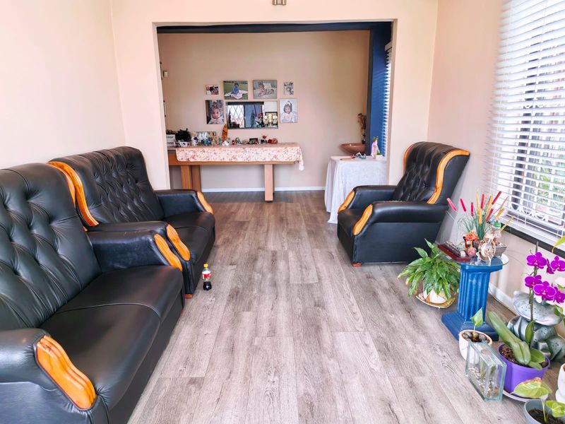 A living room featuring modern wood-look laminate flooring and venetian blinds, providing a neutral base for interior design.