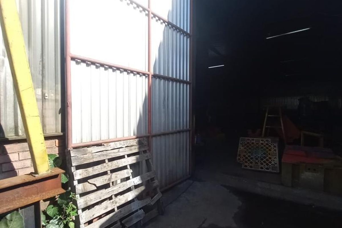 Industrial warehouse entrance featuring large sliding metal doors, corrugated steel siding, and concrete flooring, providing access to a spacious storage or workshop area.