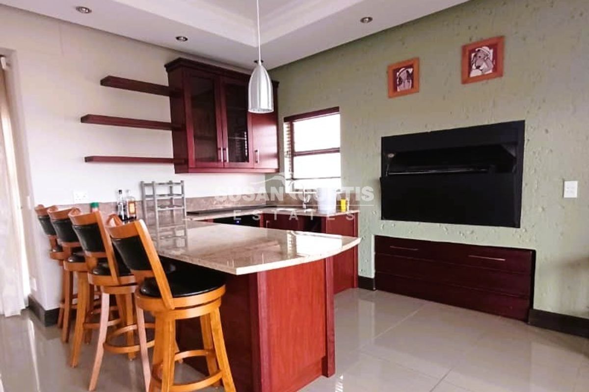 Modern kitchen featuring granite countertops, dark wood cabinetry, floating shelves, and a built-in fireplace, creating a functional and stylish living space.