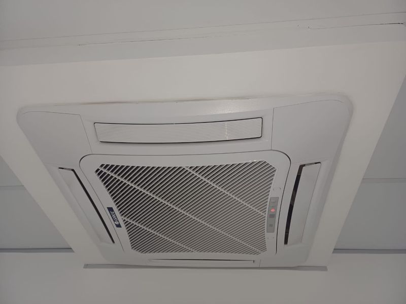 A ceiling-mounted cassette air conditioning unit installed in an office space.