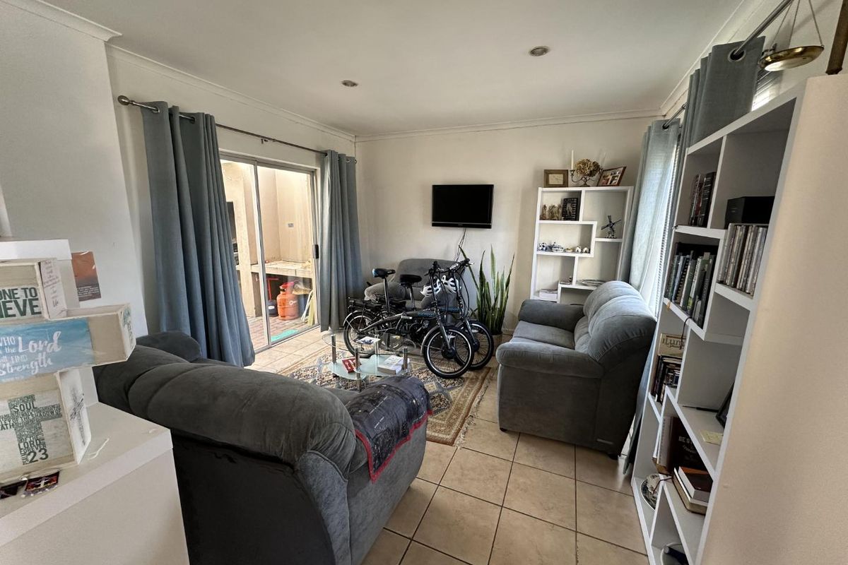 A living room featuring tiled flooring and a sliding glass door providing access to an outdoor area.