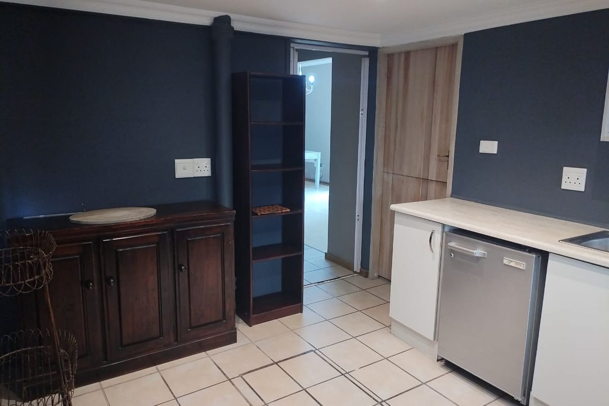 A functional kitchen area featuring tiled flooring, built-in cabinetry with laminate countertops, and an integrated dishwasher, leading into an adjacent room.