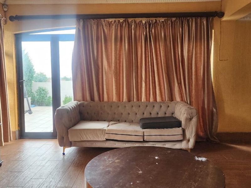 A living room featuring tiled flooring, crown molding, and a large sliding glass door providing access to the outdoor patio area.