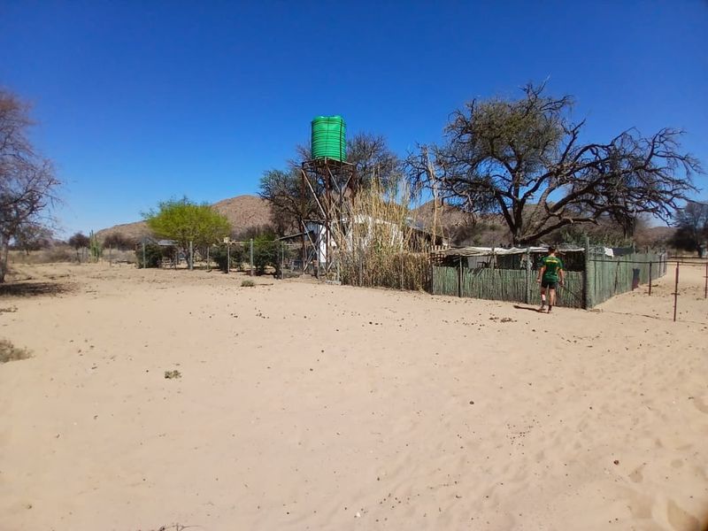 Outdoor area of a small holding featuring a raised water storage tank, wire fencing, and natural landscape.