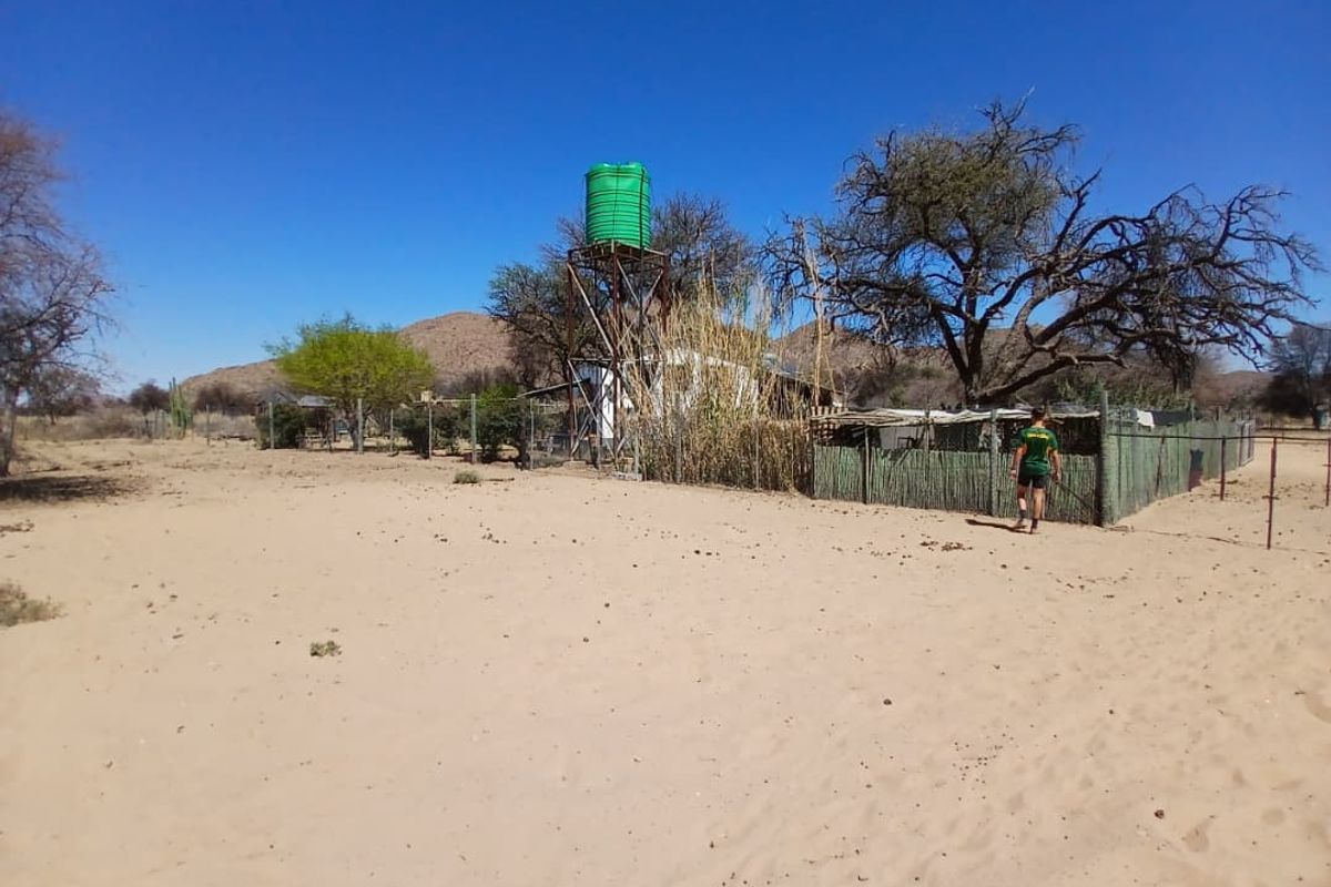 Outdoor area of a small holding featuring a raised water storage tank, wire fencing, and natural landscape.