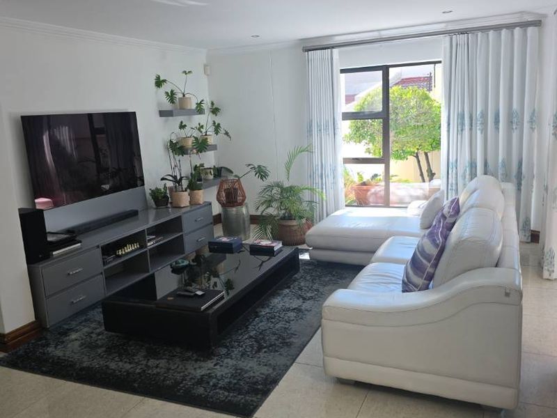 A bright and well-maintained living room featuring large windows, tiled flooring, and recessed lighting, creating a comfortable and inviting space.
