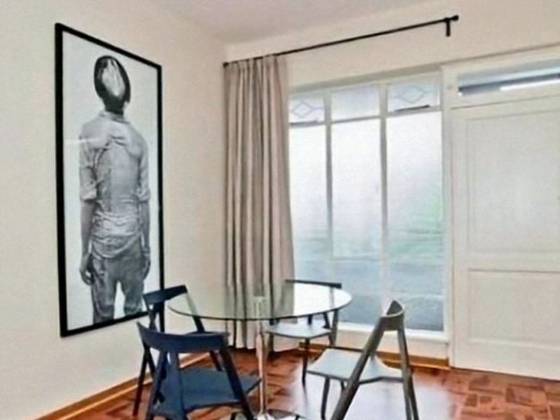 A dining area featuring classic parquet flooring, a large window with a curtain rod, and a traditional panel door.
