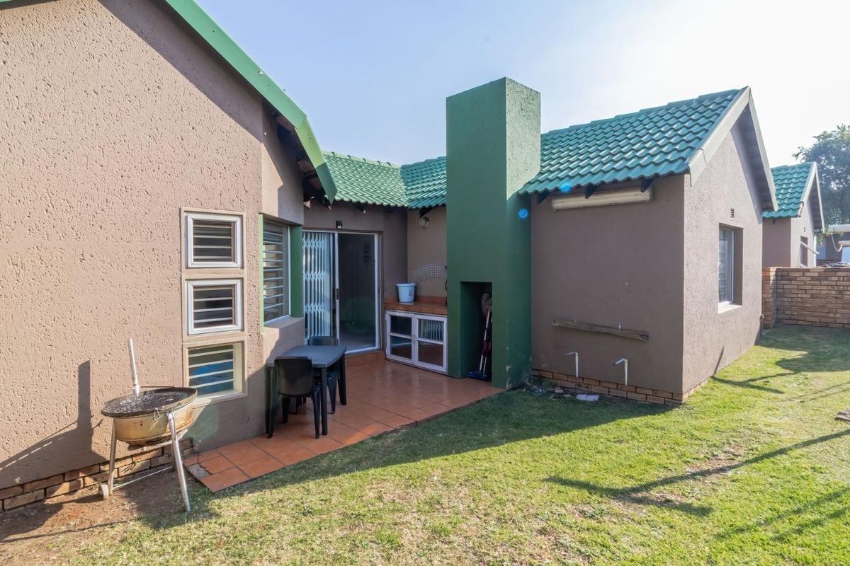 Rear view of the townhouse featuring a tiled patio area with a built-in braai, sliding door access, and a private garden space.