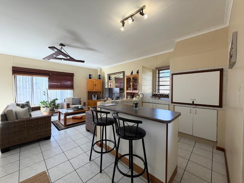 Open plan living and kitchen area featuring tiled flooring, a breakfast bar, and functional built-in cabinetry.