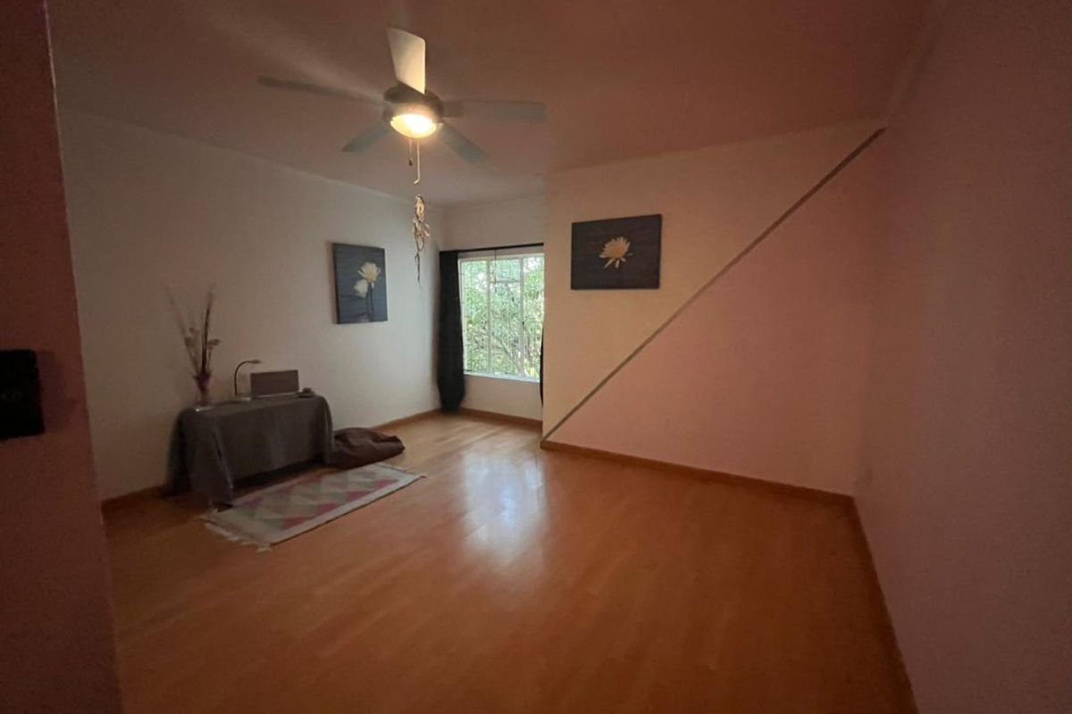 A spacious bedroom featuring light wood-look flooring, a central ceiling fan, and a large window providing natural light.