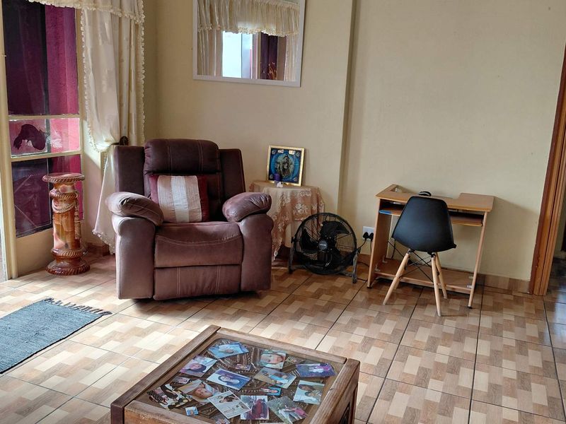 A living room area featuring tiled flooring and access to an outdoor space through a sliding glass door.