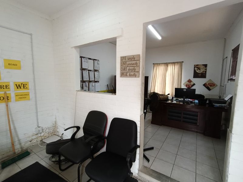 Office space featuring tiled flooring, painted brick walls, and a service window connecting to an adjacent workspace.